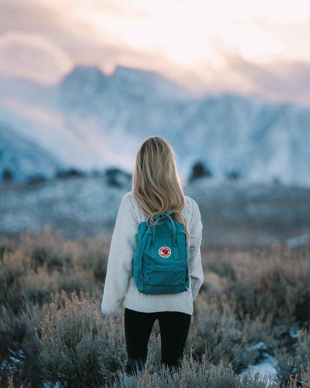 Girl Looks Out Over the Mountains at Sunset with Fjallraven Kanken Backpack